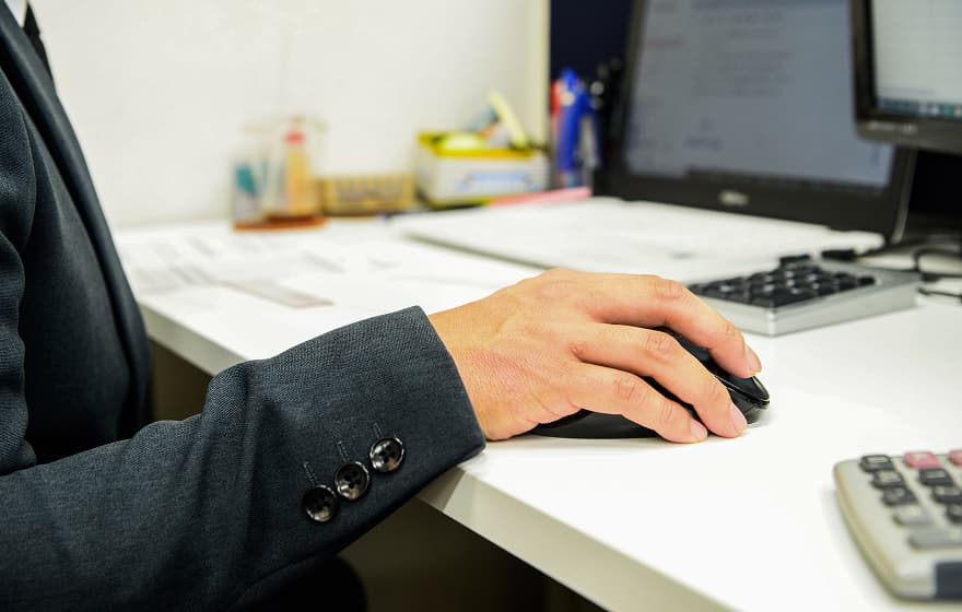 電卓とマウスを操作している手元の写真