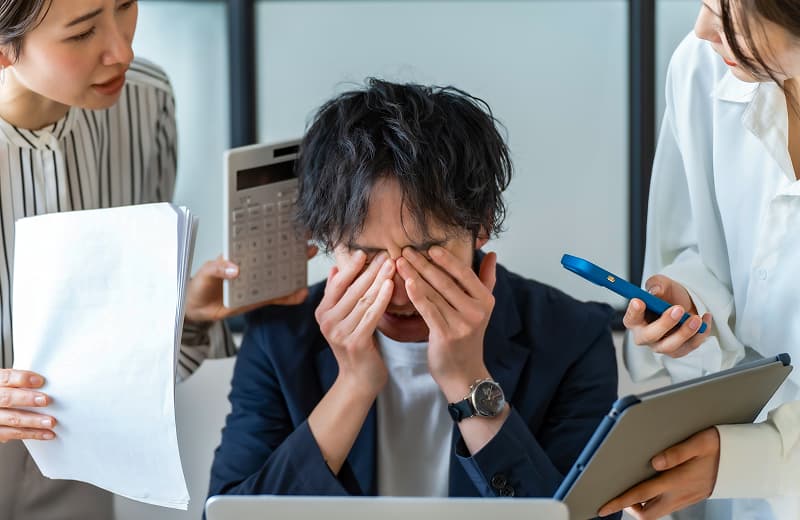 書類を前に目を覆っている男性の写真