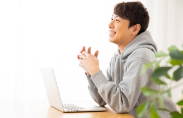 男性がパソコンの前で笑顔の写真