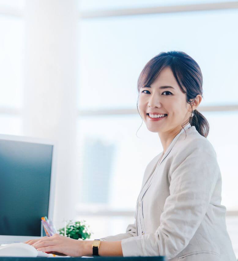 笑顔でデスクワークをする女性の写真